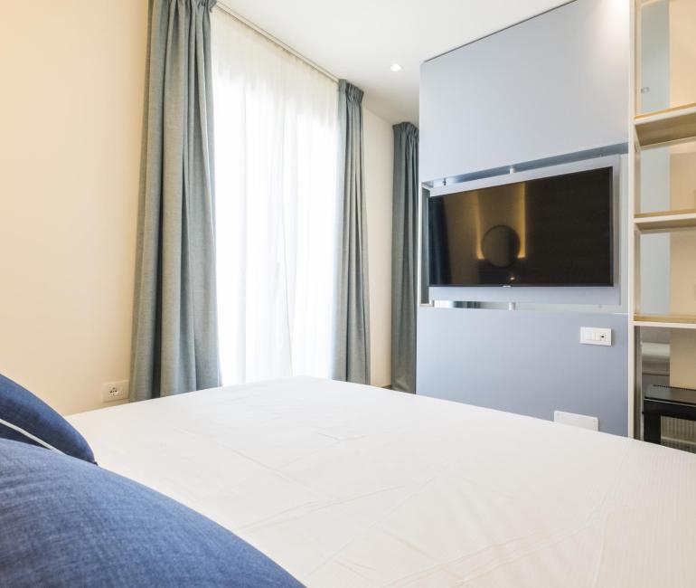 Helles Zimmer mit blauen Vorhängen und modernem Fernseher.