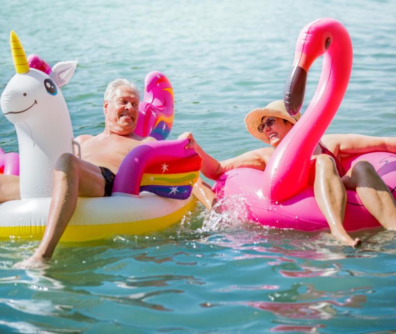 Due persone felici su gonfiabili colorati, godendo il sole e l'acqua.