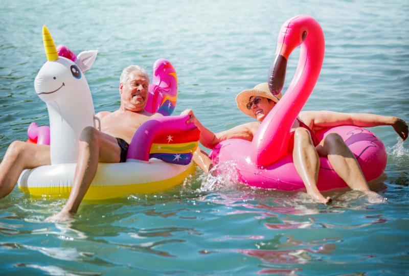 Due persone felici su gonfiabili colorati, godendo il sole e l'acqua.