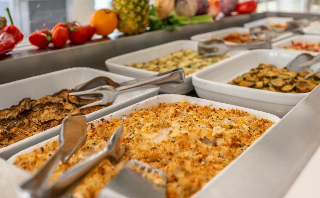 Buffet con vari piatti, tra cui gratin e verdure al forno.