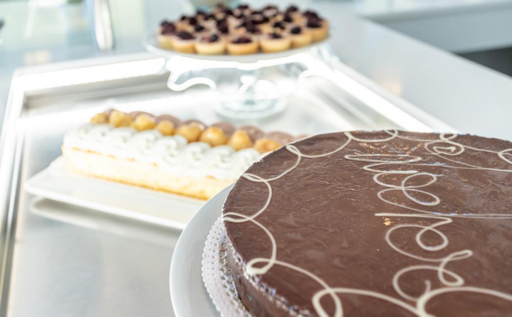 Torta al cioccolato decorata, dolci alla crema e crostatine ai frutti di bosco.