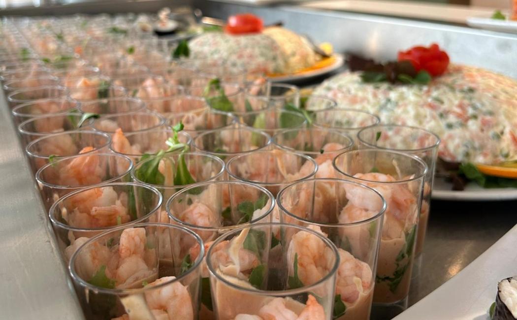 Bicchierini con gamberi e salsa, insalata russa sullo sfondo.