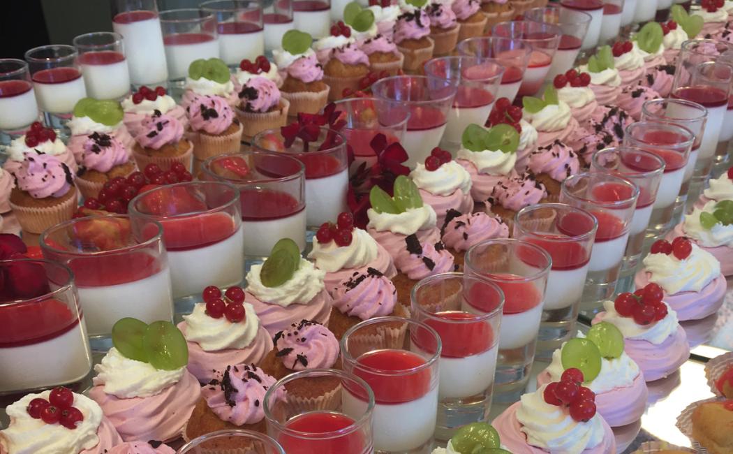 Dolci assortiti con panna, frutta e bicchierini di crema.
