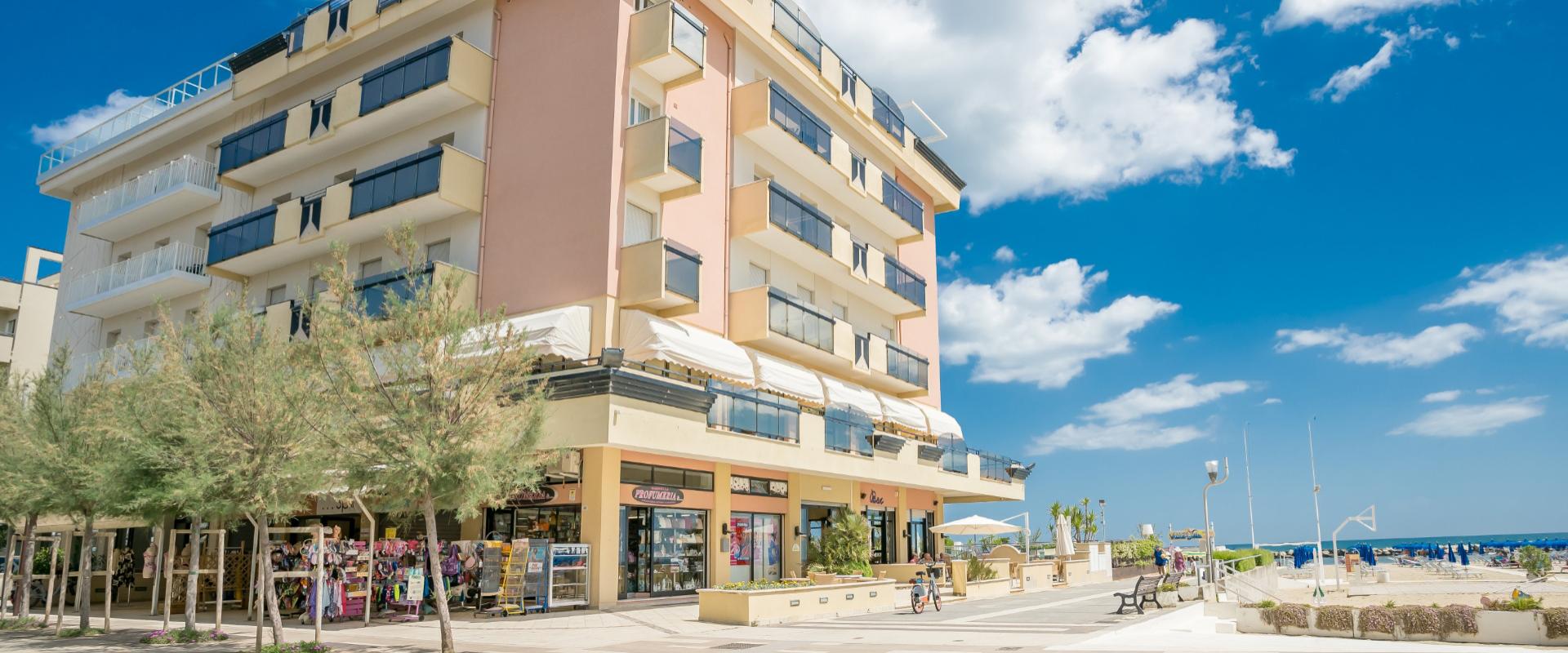 Edificio moderno vicino alla spiaggia con negozi al piano terra e balconi.
