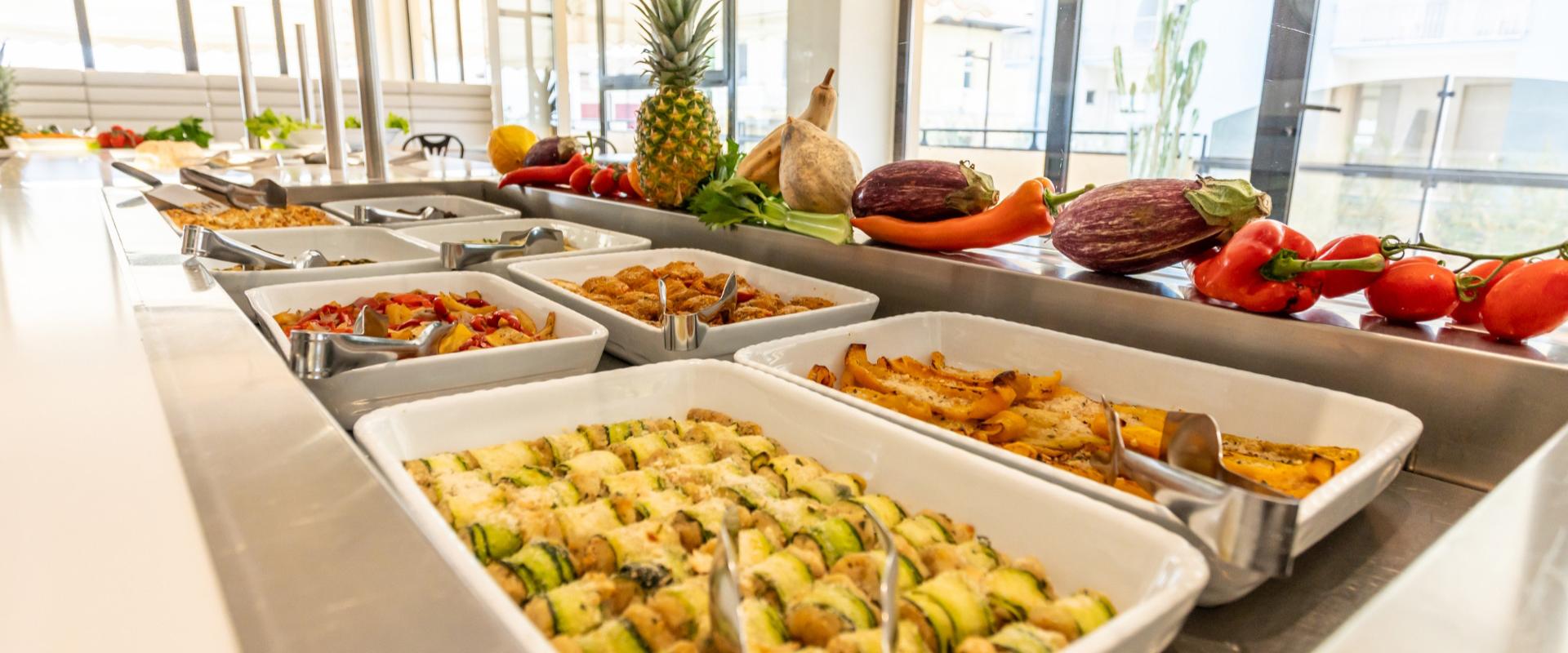 Buffet con varietà di piatti e decorazioni di frutta e verdura fresca.