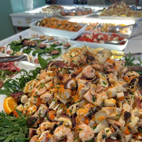 Insalata di mare con gamberi, polpo e verdure su letto di rucola e arancia.