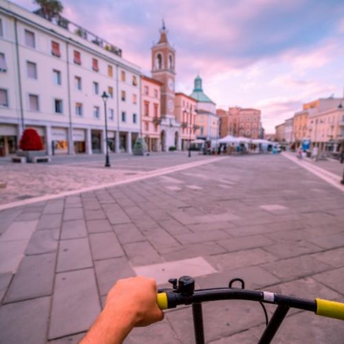 Vista di una piazza italiana al tramonto, ripresa da una bicicletta.