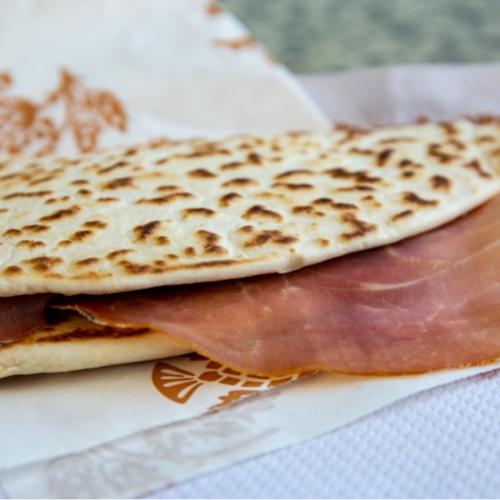 Piadina con prosciutto crudo, tipico street food italiano, servita su carta.