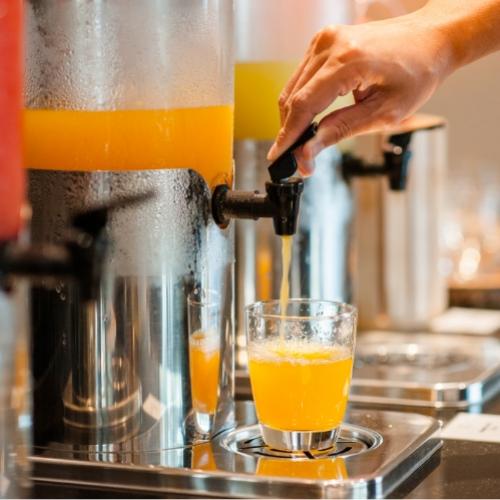 Distributore di succo d'arancia con bicchiere in fase di riempimento.